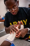 U.S. Army Spc. Jaylen Bussey, a Medical Education and Training Campus Occupational Therapy Assistant course student assigned to the 264th Medical Battalion, molds a custom splint to another student’s wrist and hand at Joint Base San Antonio-Fort Sam Houston on June 16, 2026. This section of the course teaches students to soften thermoplastic in a water bath at approximately 140°F to 160°F, then mold it directly to the patient's anatomical landmarks. These custom splints support tissue healing and joint rehabilitation.