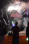 JOINT MULTINATIONAL READINESS CENTER, Germany -- Spc. Jose Mendoza, a Soldier with the Joint Multinational Readiness Center, holds a flag up as he watches fireworks light up the sky during Hohenfels' Freedom Fest. U.S. Army Garrison Bavaria hosted its annual Freedom Fest July 3, 2024, at Warrior Field at the 1st Battalion, 4th Infantry Regiment cantonment to celebrate the United States' 248th anniversary. (U.S. Army photo by Bryan Gatchell, USAG Bavaria Public Affairs)
