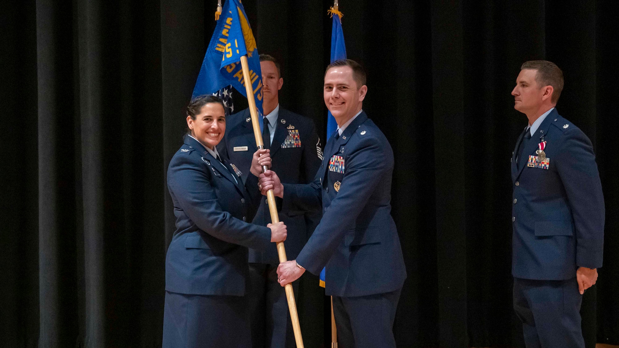 Col. Paola Ondina, left, passes the guidon to Lt. Col. Mason Workman during the GXS change of command ceremony.