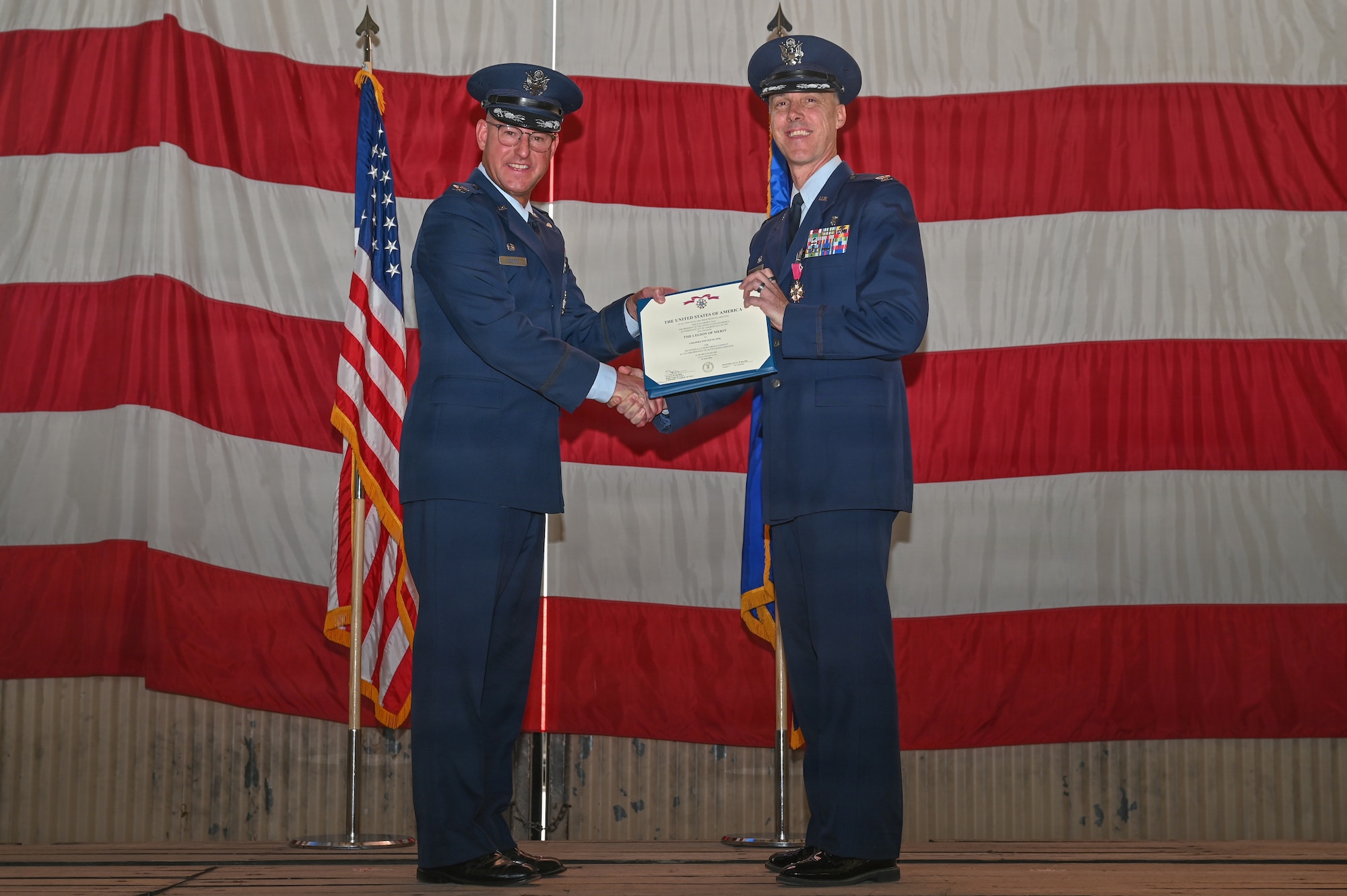 U.S. Air Force Col. Justin D. Secrest, 377th Air Base Wing and installation commander, presents the Legion of Merit award to Col. Steven M. Fox, outgoing Kirtland Medical Group commander, during the Kirtland Medical Group change of command ceremony at Kirtland Air Force Base.