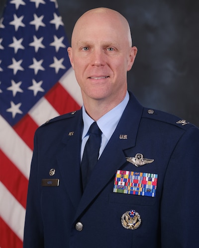 photo of USAF Airman standing in front of a US flag