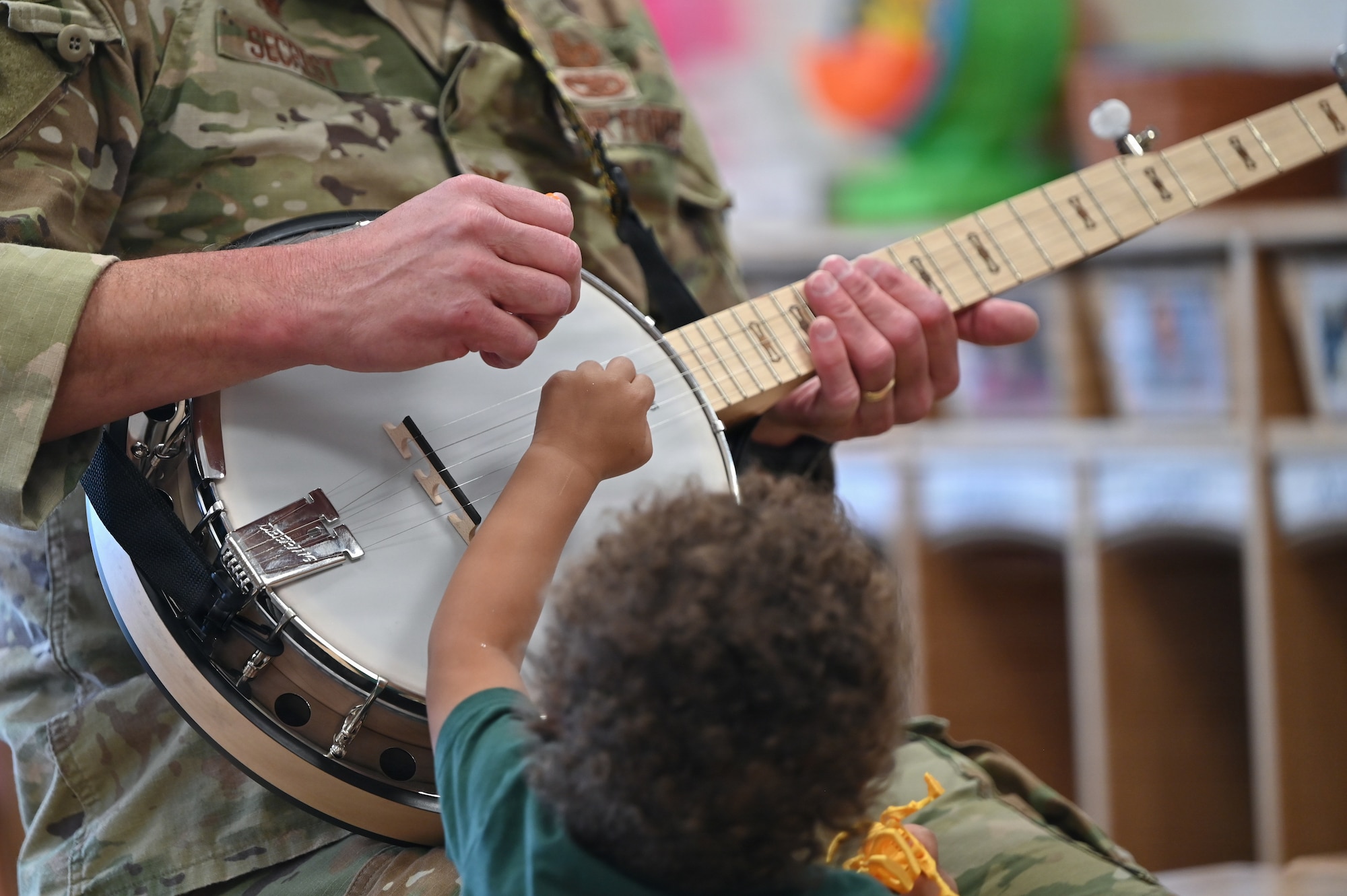 U.S. Air Force Col. Justin D. Secrest, 377 Air Base Wing and installation commander, interacts with children through the banjo at Maxwell Child Development Center at Kirtland Air Force Base.