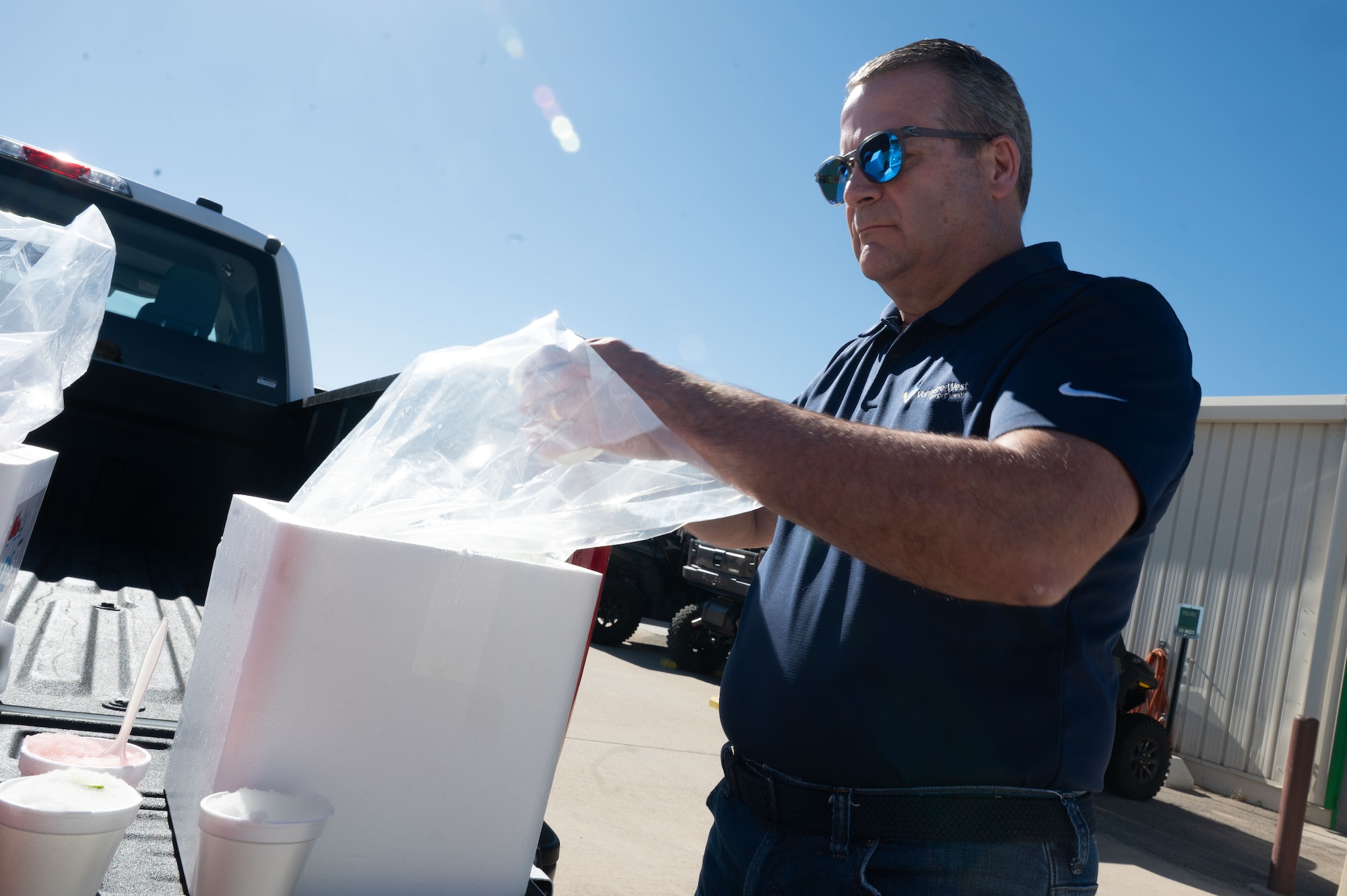 A DM50 member, serves shaved ice on the flightline at Davis-Monthan Air Force Base, Arizona, July 2, 2026. DM50, the Military Affairs Committee and base first sergeants aimed to boost morale and show appreciation for Airmen enduring high temperatures on the flight line and in other outdoor areas by handing out shaved ice. (U.S. Air Force photo by Airman 1st Class Jaden Kidd)