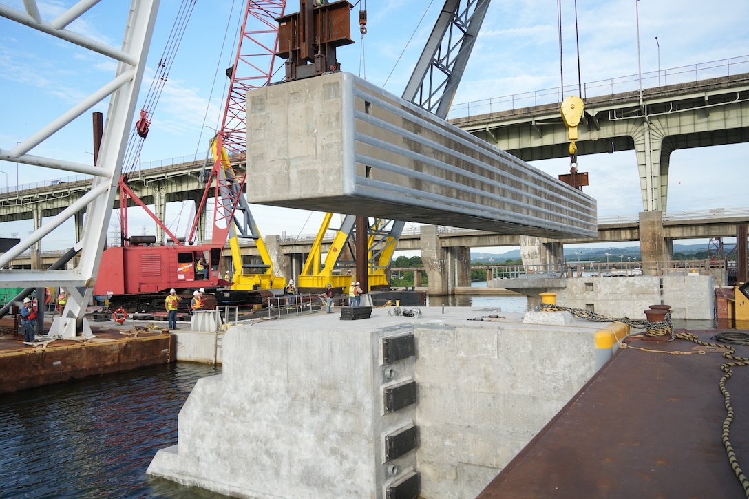 A 420-ton concrete beam is hoisted into position over the Tennessee River during construction of the upstream approach wall for the Chickamauga Lock Replacement Project, June 16, 2026, in Chattanooga, Tenn. The successful placement of these massive beams, guided by contractors on the pier below, marks a significant milestone in the U.S. Army Corps of Engineers' mission to modernize the nation's inland waterways and deliver critical navigation infrastructure. (USACE Photo by Noe Gonzalez)