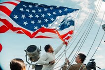 Quartermaster 3rd Class Enrique Rubio, left, from Texas, and Senior Chief Quartermaster Robert McInerery, from Pennsylvania, assigned to Navigation department, lower the battle Ensign aboard Nimitz-class aircraft carrier USS George Washington (CVN 73) while underway in the Philippine Sea, July 2, 2026.