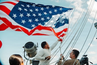 Quartermaster 3rd Class Enrique Rubio, left, from Texas, and Senior Chief Quartermaster Robert McInerery, from Pennsylvania, assigned to Navigation department, lower the battle Ensign aboard Nimitz-class aircraft carrier USS George Washington (CVN 73) while underway in the Philippine Sea, July 2, 2026.