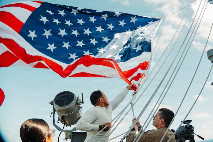 Quartermaster 3rd Class Enrique Rubio, left, from Texas, and Senior Chief Quartermaster Robert McInerery, from Pennsylvania, assigned to Navigation department, lower the battle Ensign aboard Nimitz-class aircraft carrier USS George Washington (CVN 73) while underway in the Philippine Sea, July 2, 2026.