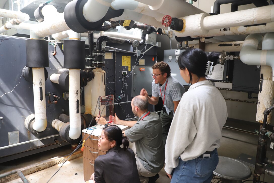 Practicum instructor Jay Tulley (center, with glasses), research engineer at the U.S. Army Engineer Research and Development Center’s Construction Engineer Research Laboratory (ERDC-CERL), leads a session on air handler units in a mechanical room at ERDC-CERL.