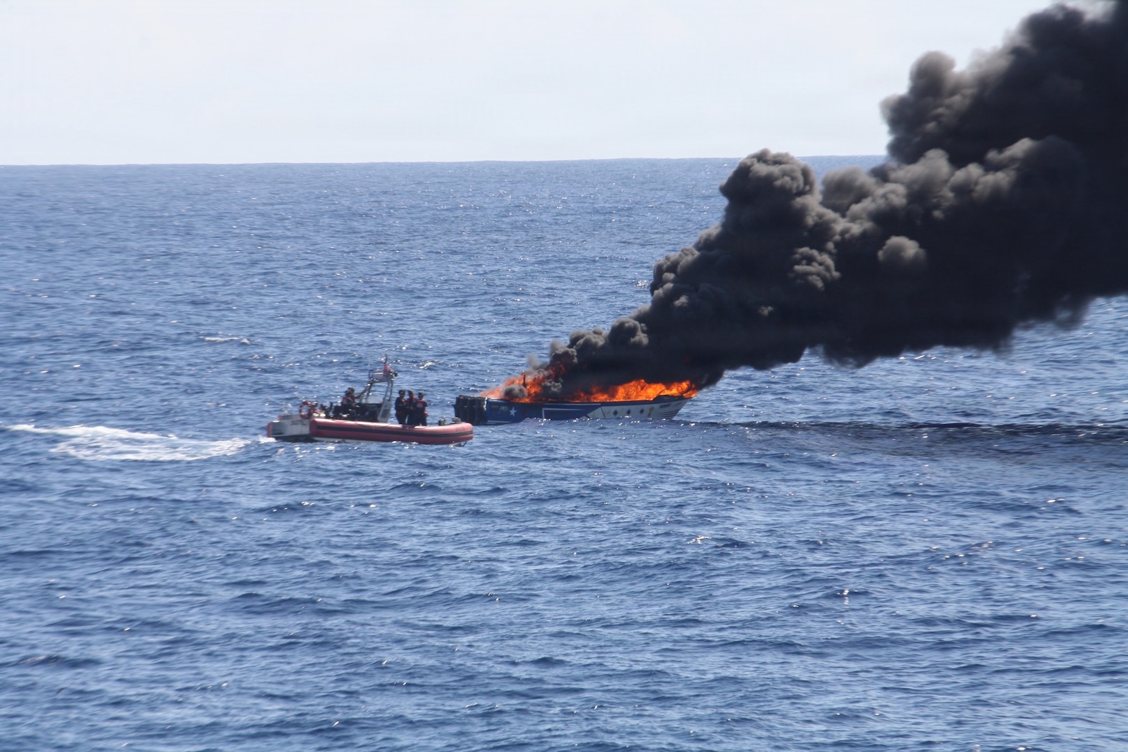 A small boat crew from the Coast Guard Cutter Bear (WMEC 901) sinks a drug-smuggling vessel after a successful interdiction in the Eastern Pacific Ocean, May 11, 2026. Due to the vessel's poor seaworthiness and lack of towing points, the Coast Guard destroyed the ship to prevent it from becoming a hazard to navigation. (U.S. Coast Guard photo)