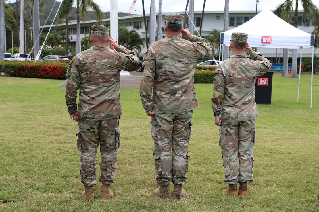 The back side of three male Army Soldiers saluting the flag