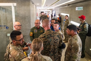 Military officers from the U.S. and Venezuela hold a discussion in a hallway.