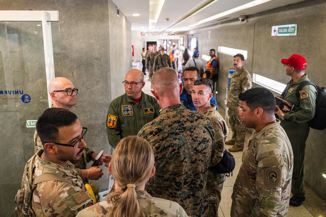 Military officers from the U.S. and Venezuela hold a discussion in a hallway.