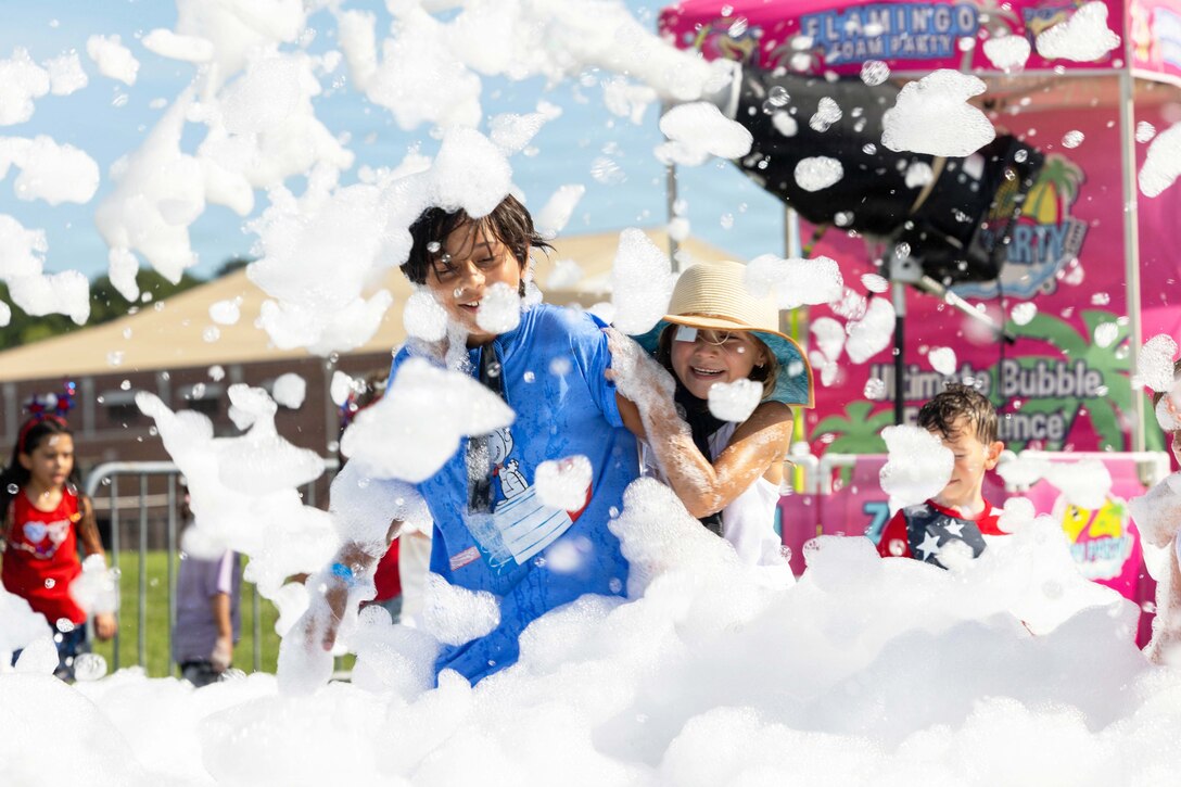 Military children play in bubbles during the day.