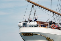 U.S. Coast Guardsmen wave to onlookers on a boat.
