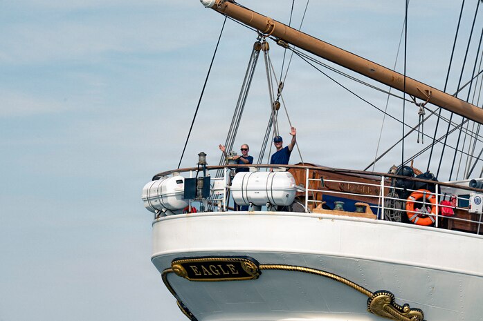 U.S. Coast Guardsmen wave to onlookers on a boat.
