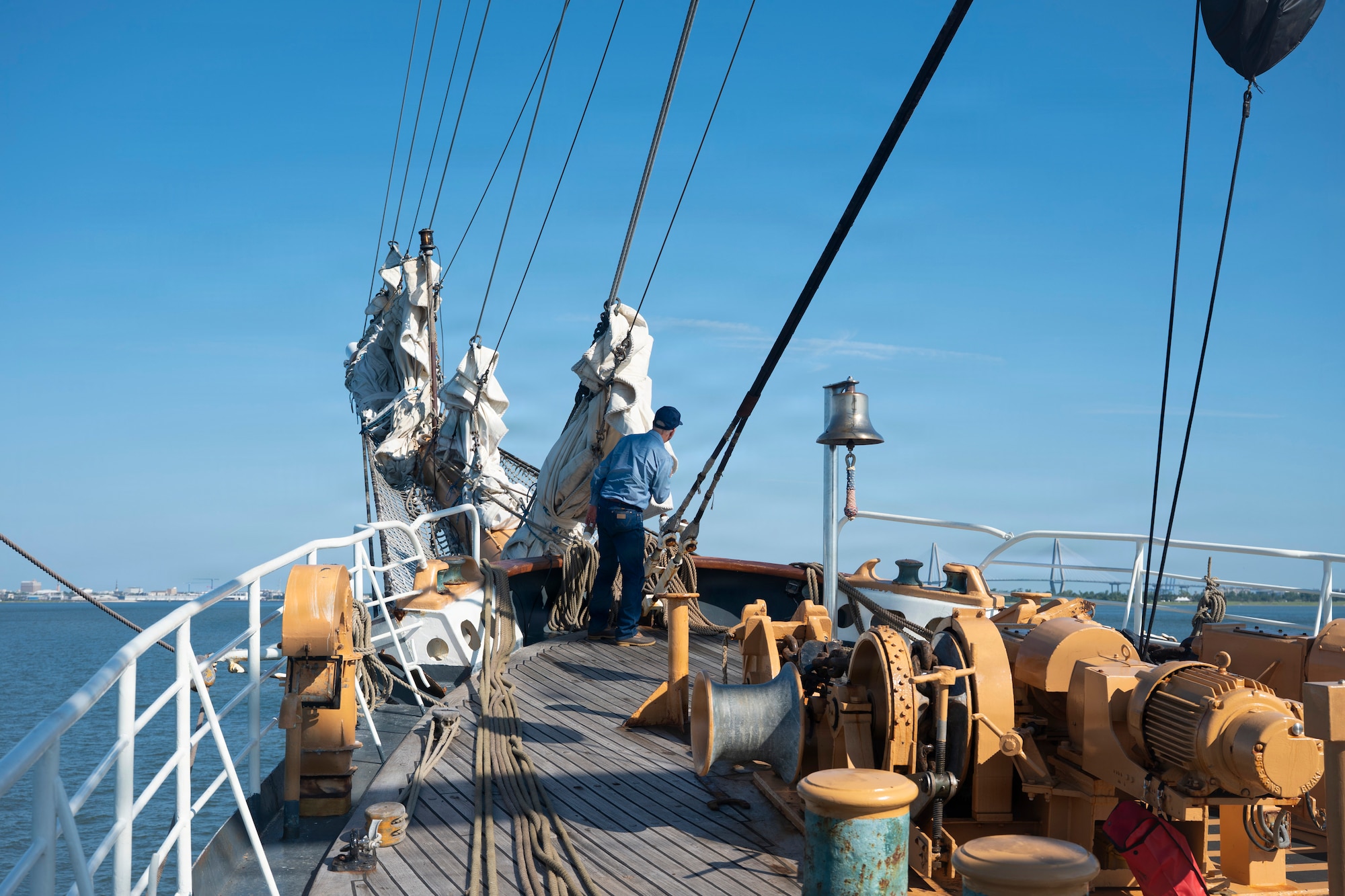 A person looks out to the horizon while standing on a boat.