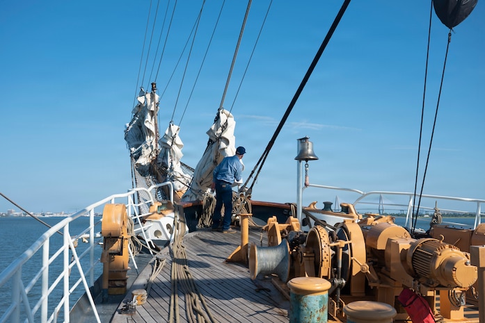 A person looks out to the horizon while standing on a boat.