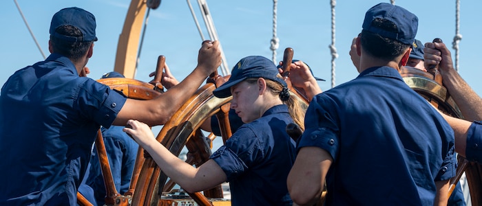 U.S. Coast Guard Academy cadets operate a ship wheel.