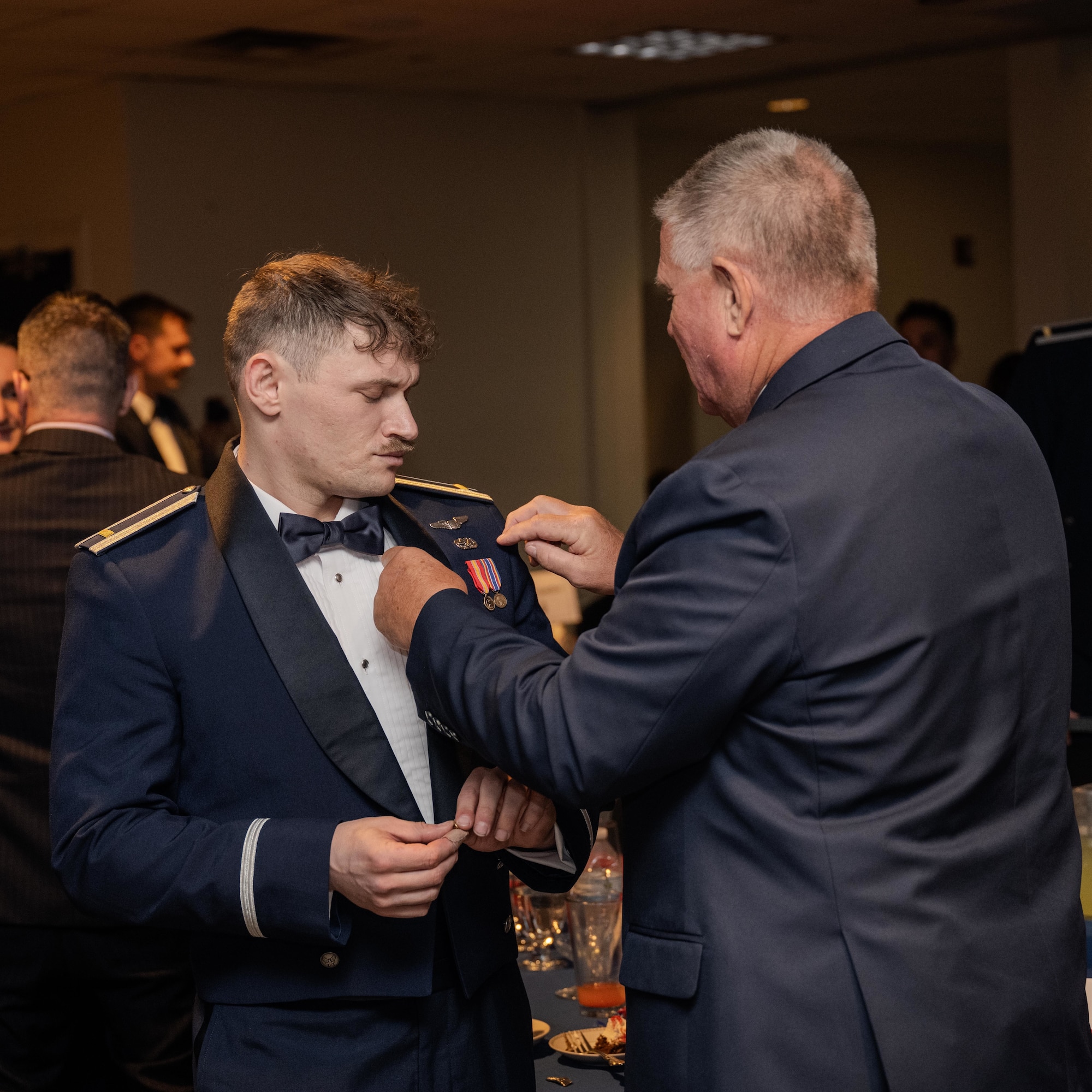 U.S. Air Force 2nd Lt.  Matthew Morehead, 47th Student Squadron student pilot, receives his silver wings with assistance from his guest during the graduation ceremony of Class 26-13 at Laughlin Air Force Base, Texas, July 1, 2026. Twenty-two U.S. Air Force officers were awarded silver wings during the ceremony, symbolizing their completion of the Undergraduate Pilot Training program. (U.S. Air Force photo by Airman 1st Class Harrison Sullivan)