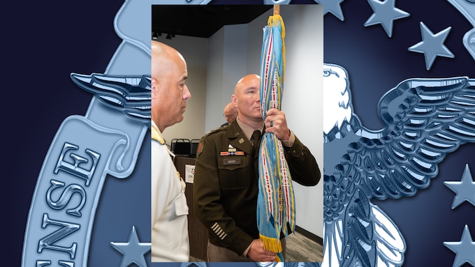 The incoming Defense Logistics Agency Energy Americas Commander holds the unit guidon.