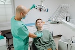 Dentist adjusts the light over a patient sitting in the dentist's chair.