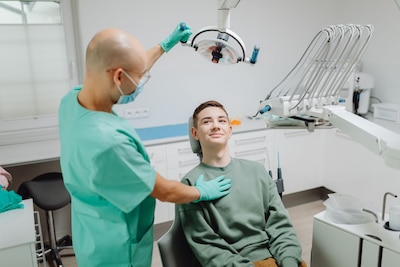 Dentist adjusts the light over a patient sitting in the dentist's chair.
