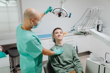 Dentist adjusts the light over a patient sitting in the dentist's chair.