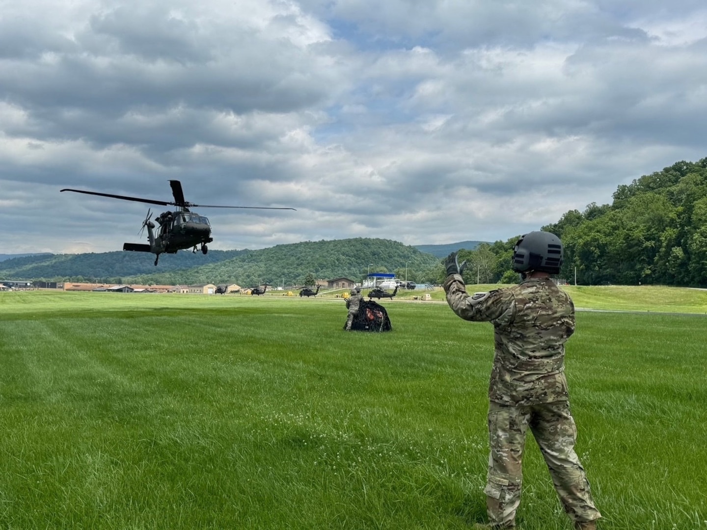 A crew chief assigned to Charlie Company, 131st Aviation Regiment, uses hand-and-arm signals to guide a UH-60M Black Hawk helicopter during sling-load training at Camp Dawson, West Virginia, June 4, 2026.
