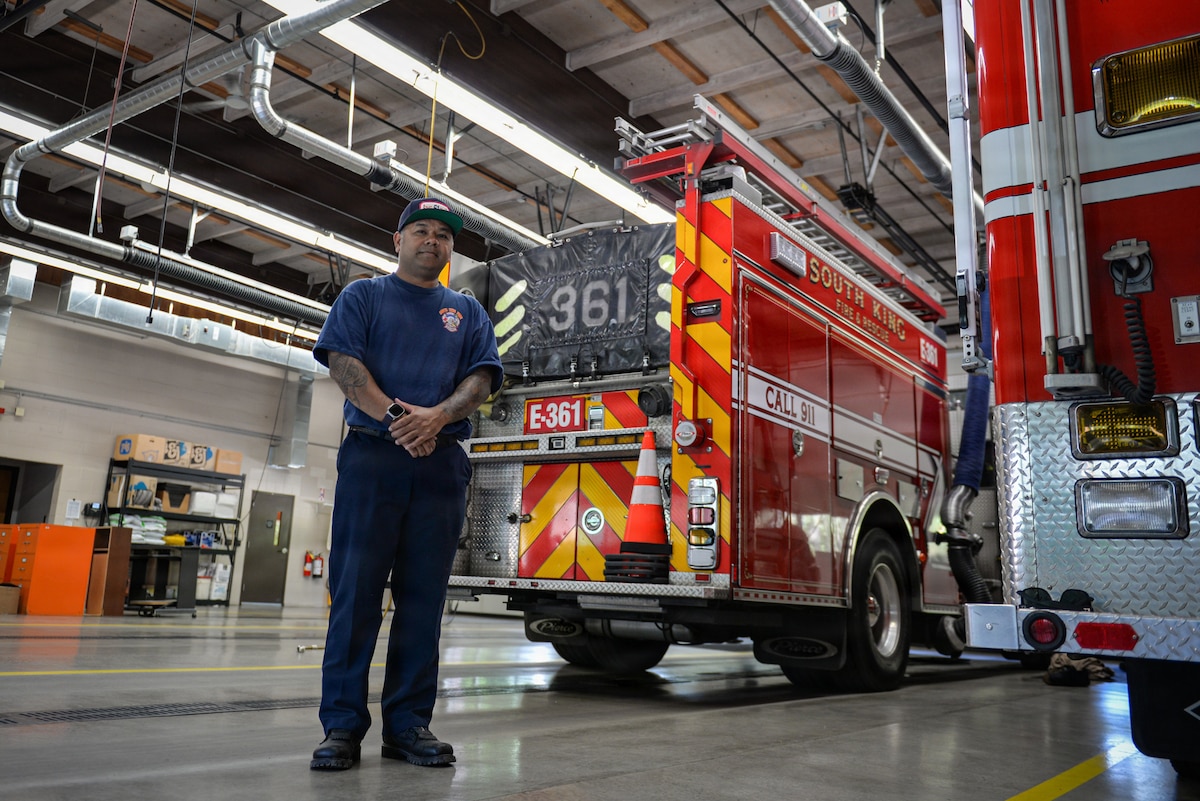 Firefighter poses for a photo in front of a fire truck