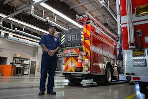 Firefighter poses for a photo in front of a fire truck