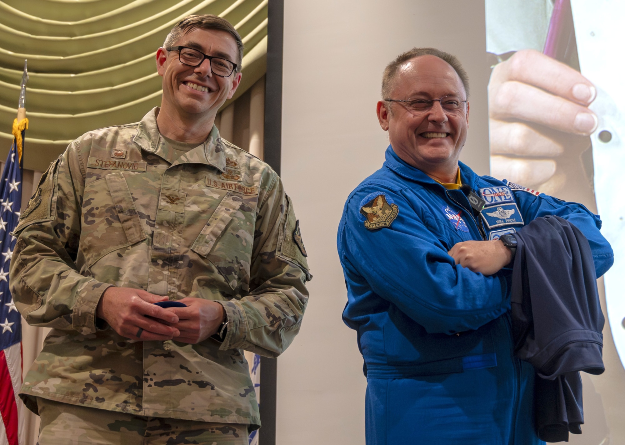 Retired U.S. Air Force Col. and NASA astronaut Michael Fincke (right) displays the Joint Base McGuire-Dix-Lakehurst patch on his shoulder given to him by U.S. Air Force Col. Michael Stefanovic, JB MDL and 87th Air Base Wing commander, during his presentation to personnel at JB MDL, N.J., June 22, 2026. Fincke, who joined the NASA astronaut corps in 1996 and has accumulated 549 days in space, brought his decades of military and spaceflight experience to the installation, speaking to both joint base personnel and their children during his visit. (U.S. Air Force photo by Susan Moriarty)