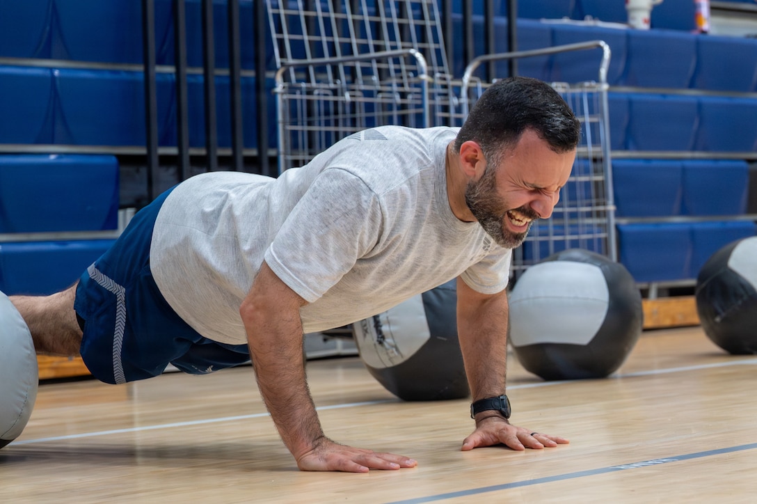 An Airmen planks in a gym.