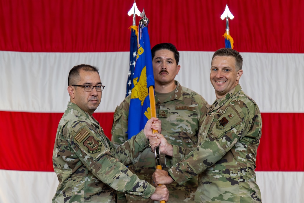 Man passes guidon to another during a ceremony.