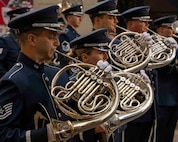Airmen facing right play French horns in a line, the profile view highlights the overlapping curves of the horns.