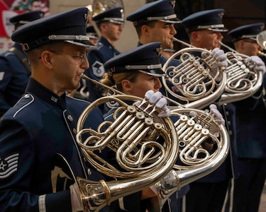 Airmen facing right play French horns in a line, the profile view highlights the overlapping curves of the horns.