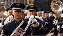 Airmen play silver instruments in formation.