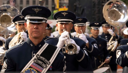 Airmen play silver instruments in formation.