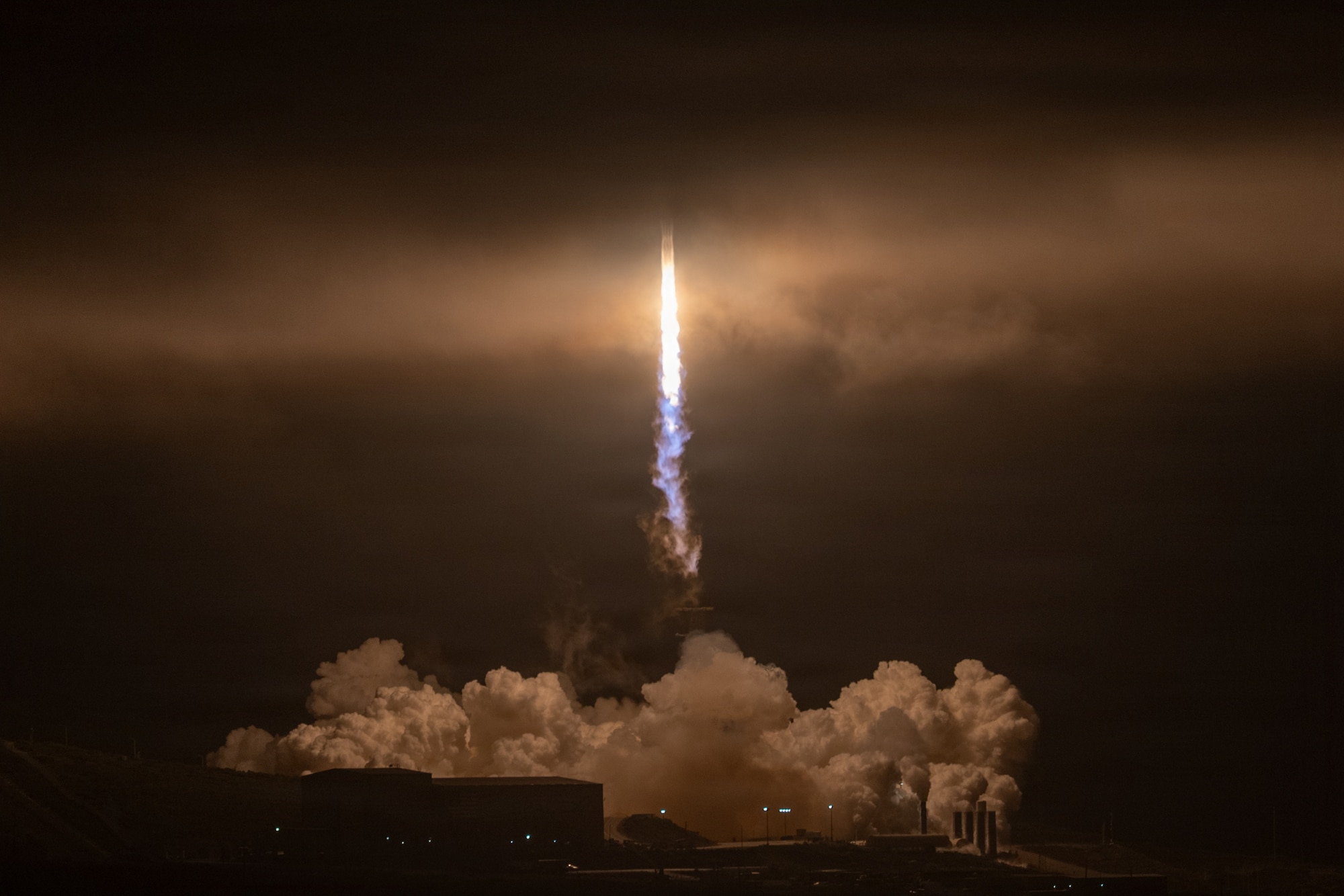 The flames of a rocket enter the marina layer.