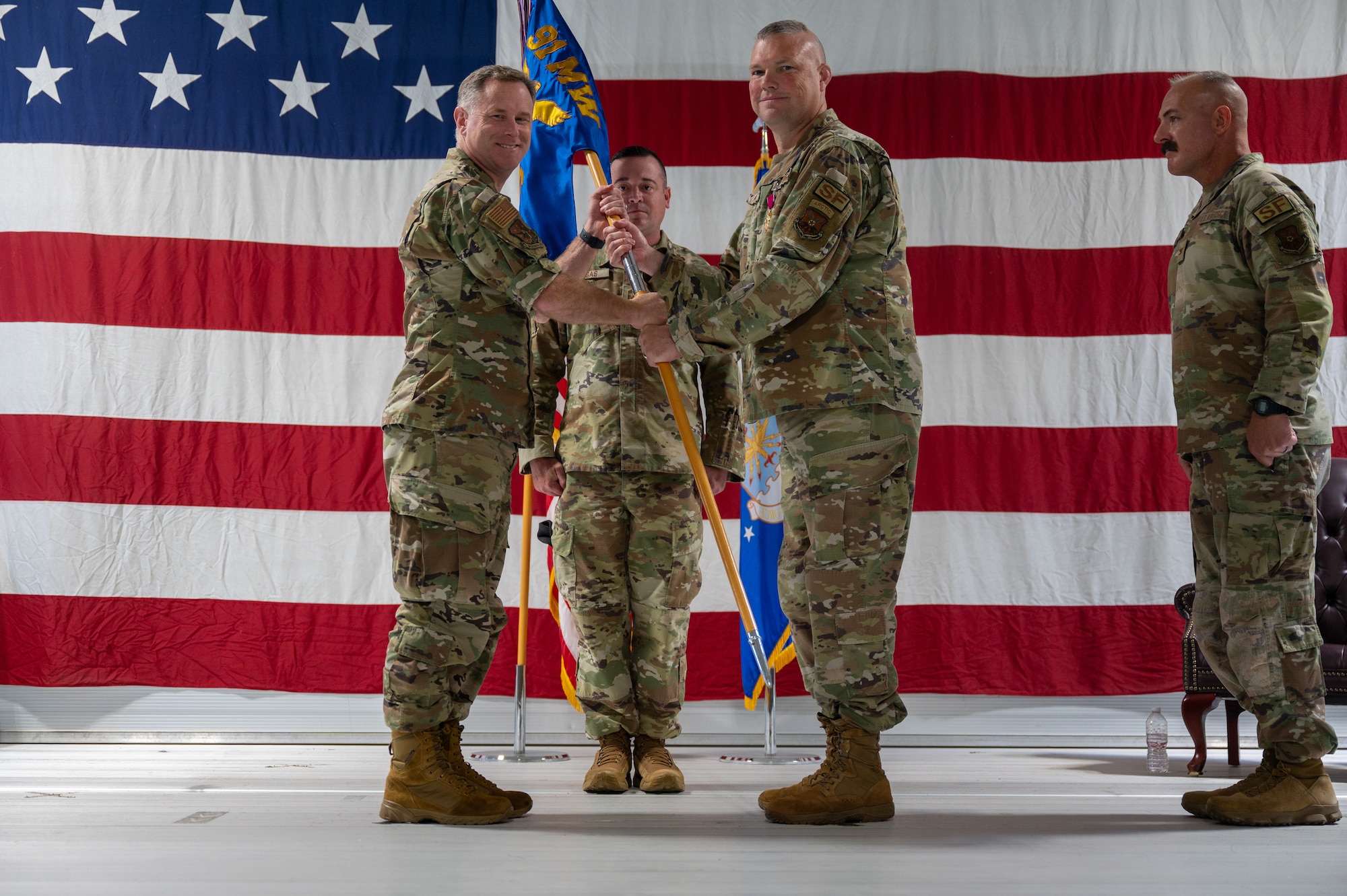 U.S. Air Force Col. Jimmy Schlabach, 91st Missile Wing commander, left, receives the guidon from U.S. Air Force Col. James Slaton, 91st Security Forces Group (SFG) commander, during a change of command ceremony at Minot Air Force Base, North Dakota, July 1, 2026. As the 91st SFG commander, Slaton was primarily responsible for maintaining the security of the Minuteman III missile silos in the surrounding area.