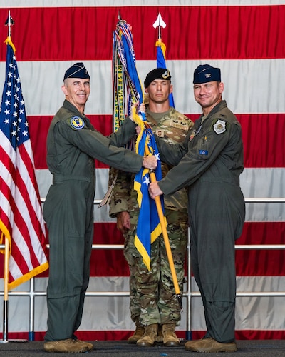 A general and a pilot hold a guidon
