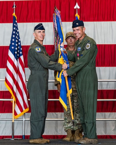A general and a pilot hold a guidon