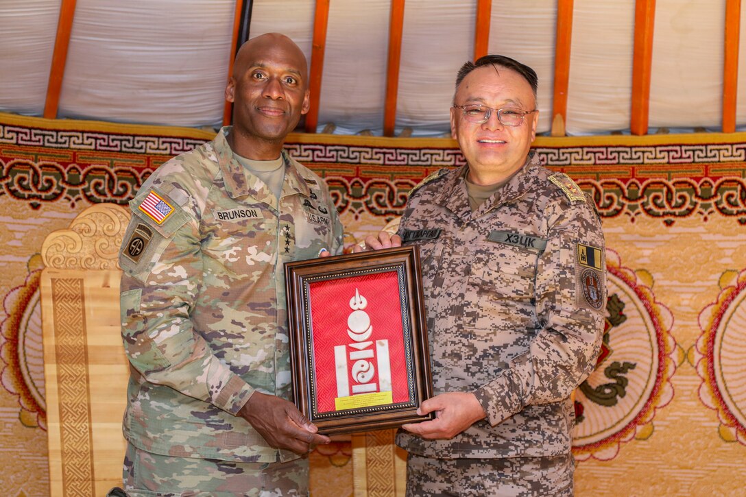 U.S. Army Gen. Xavier T. Brunson and Mongolian Maj. Gen. Chimedgochoo Tsogtjargal stand together in military uniforms as the Mongolian commander presents a gift to Gen. Brunson at the Five Hills Training Area near Ulaanbaatar, Mongolia, during exercise Khaan Quest 2026.