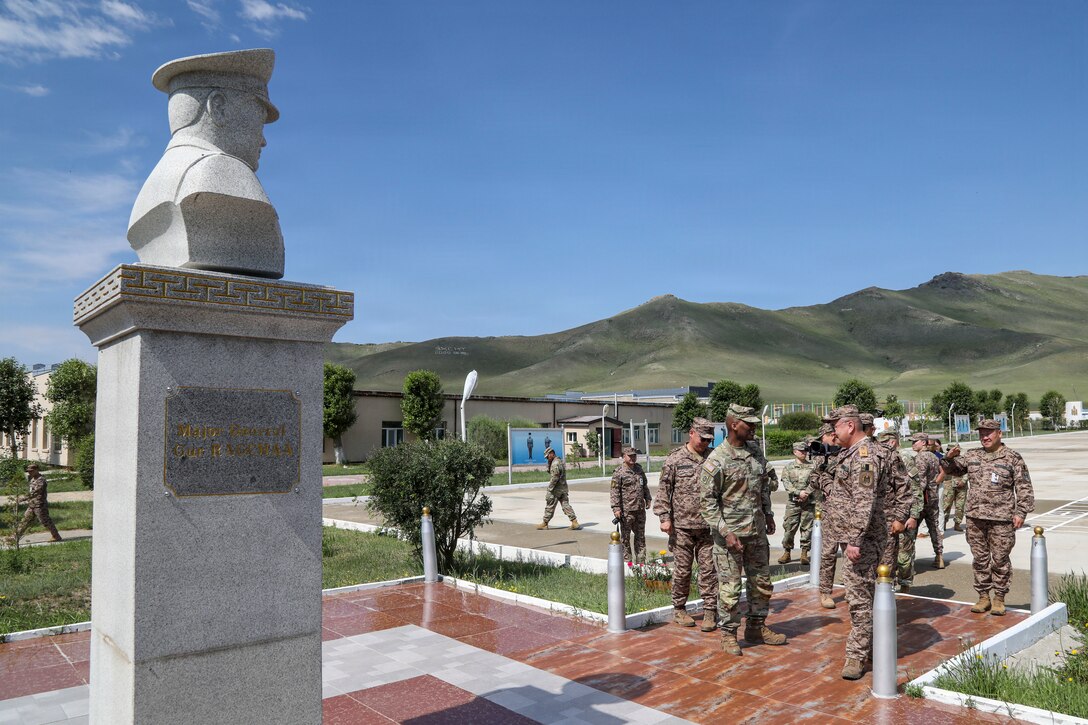 U.S. Army Gen. Xavier T. Brunson, alongside U.S. Army and Mongolian Armed Forces senior leaders, stands in front of the statue of Mongolian Maj. Gen. Güriin Ragchaa outdoors at the Five Hills Training Area in Mongolia.