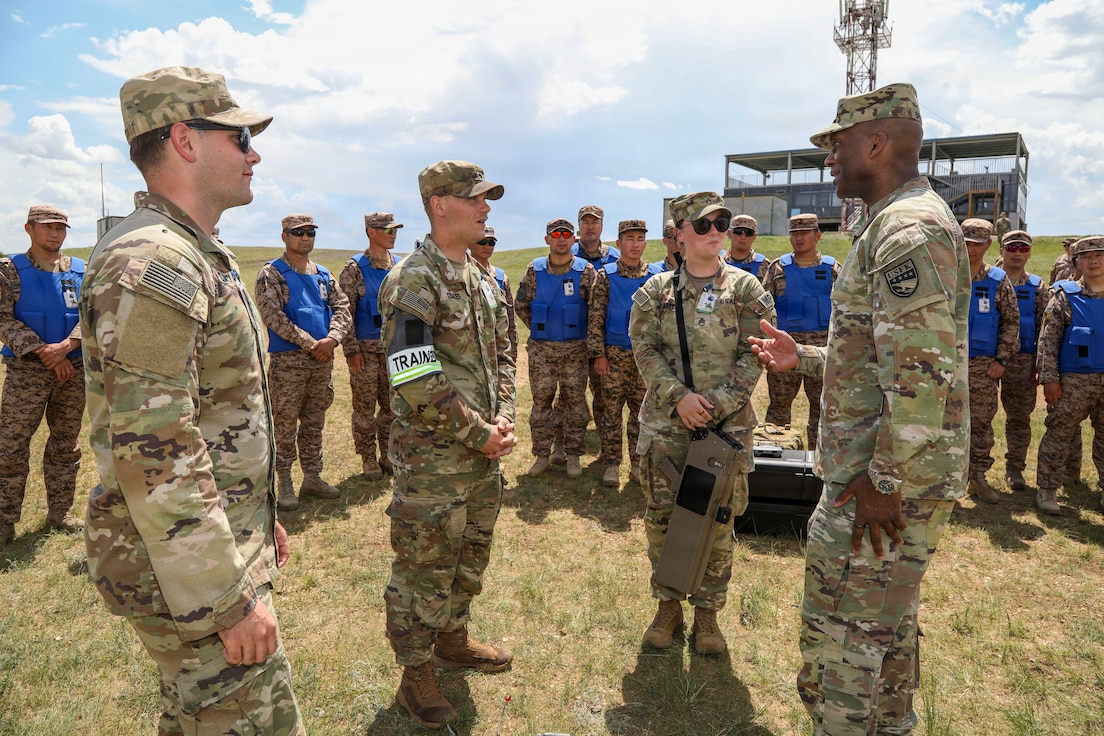 U.S. Army Gen. Xavier T. Brunson, commander of United Nations Command and Combined Forces Command, stands on the right in military uniform, speaking with U.S. Army Soldiers from the 8th Military Police Brigade outdoors at the Five Hills Training Area in Mongolia.