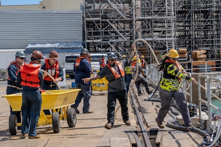 Sailors and shipyard employees work together to heave in line during the undocking of Virginia-class fast-attack submarine USS Illinois (SSN 786) from Dry Dock 2 at Pearl Harbor Naval Shipyard and Intermediate Maintenance Facility (PHNSY & IMF).