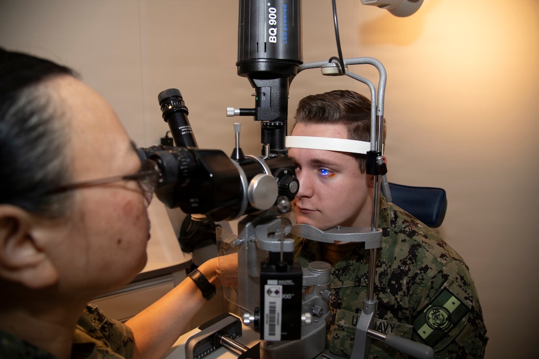 260618-N-N1526-1006 (June 18, 2026) BETHESDA, Md. U.S. Navy Cmdr. Hong Gau, aerospace optometrist assigned to Walter Reed National Military Medical Center, conducts an eye exam to look for signs of eye disorders, such as cataracts or glaucoma, on Hospital Corpsman 3rd Class Brighton Avey, in Bethesda, Maryland. The Navy Medicine Enterprise's 44,000+ talented and ready forces optimize health readiness, deliver quality healthcare, and provide global expeditionary medical support to warfighters. (U.S. Navy photo by Jerry S. Wright)