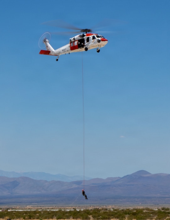260616-N-TC277-2443 U.S. Navy Chief Hospital Corpsman Albert Tran rappels from an Air Test and Evaluation Squadron (VX) 31 search and rescue helicopter during his final flight with the squadron at Naval Air Weapons Station China Lake, California, June 16, 2026. Family members and VX-31 teammates lined the flight line to watch. (U.S. Navy photo by Michael L. Smith)