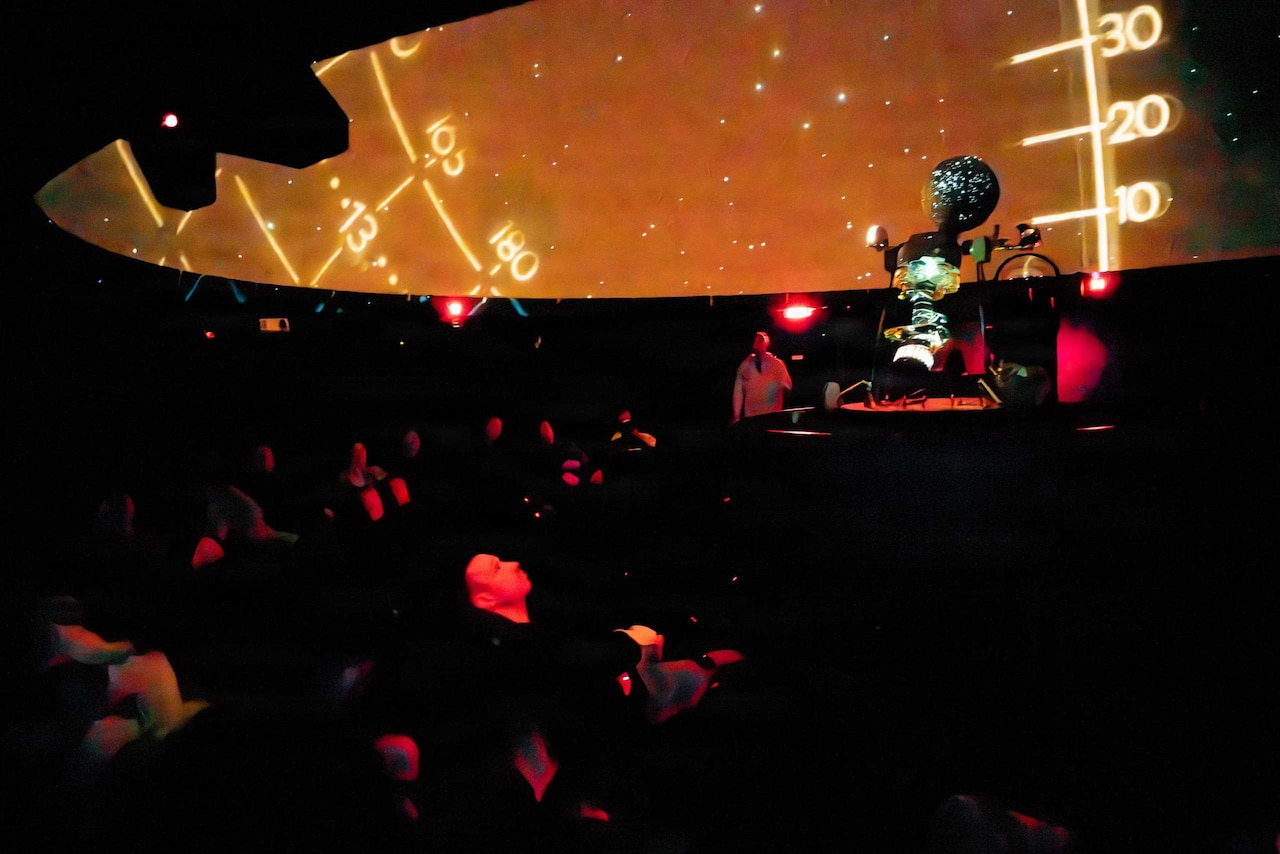 People look at a screen inside a planetarium.