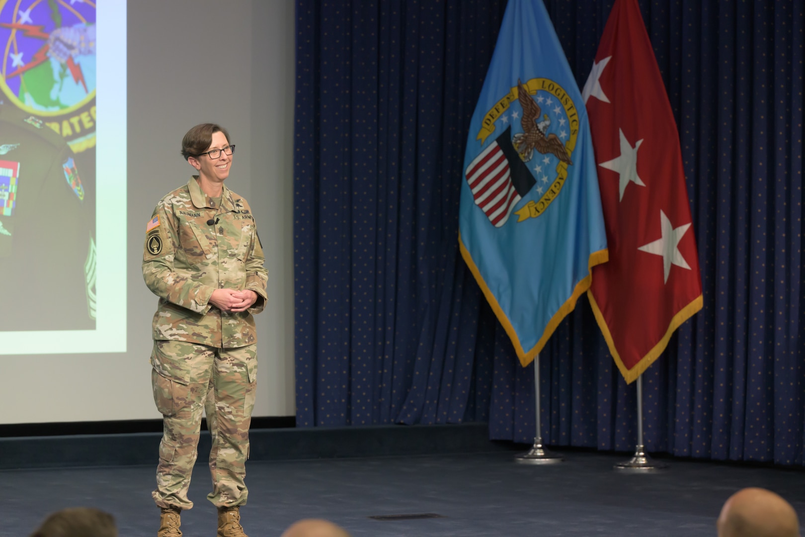 A female Army Soldier stands on a stage.