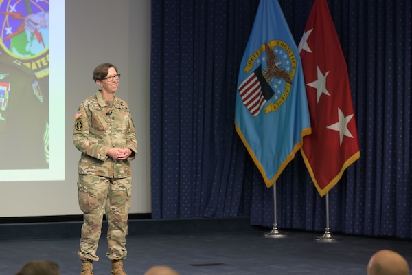 A female Army Soldier stands on a stage.